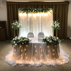 the table is set up with white flowers and greenery for an elegant wedding reception