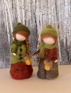 two knitted dolls sitting next to each other in front of a birch tree background