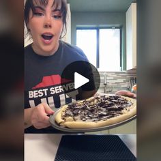 a woman holding a pizza on top of a pan