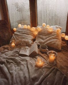 a bed topped with lots of candles next to a window