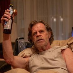 a man sitting on a couch holding a beer bottle