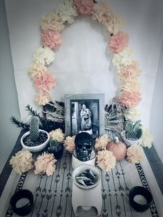 an arrangement of flowers and plants on a table with a framed photo in the middle