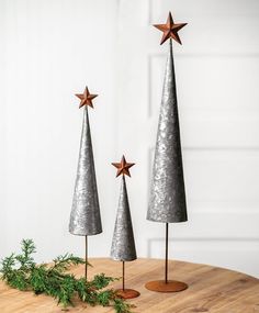 three metal christmas trees sitting on top of a wooden table