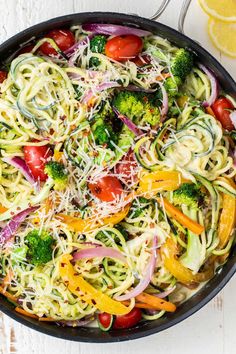 a pan filled with zucchini noodles, broccoli, tomatoes and onions