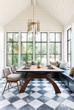 a dining room with black and white checkered flooring, chandelier and windows