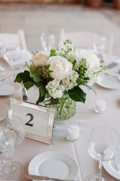 a vase filled with flowers sitting on top of a table covered in white linens