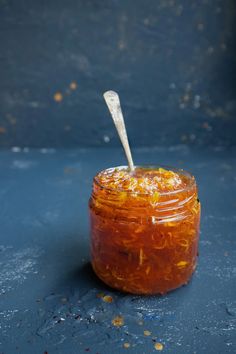 a jar filled with food sitting on top of a blue table next to a spoon