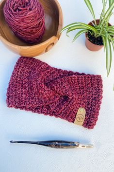 a crochet hat and yarn next to a plant