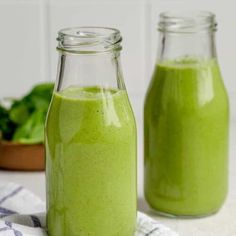 two glass jars filled with green smoothie next to each other