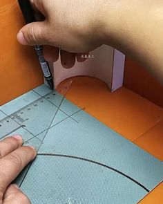 someone is cutting out a piece of paper on a table with scissors and rulers