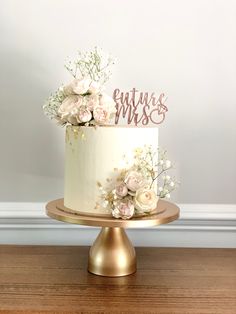 a white cake with pink flowers and the words future mrs on top is sitting on a gold plate