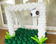 an arch made out of balloons with a soccer ball on top