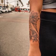 a woman with a tattoo on her arm is standing in the middle of the street