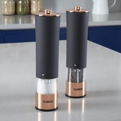 two salt and pepper grinders sitting on top of a counter