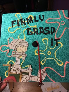 a green graduation cap with the words family grasp on it and an image of a cartoon character