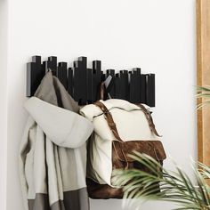 a coat rack with two coats hanging from it's sides next to a potted plant