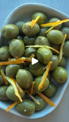 a bowl filled with green olives and orange peels