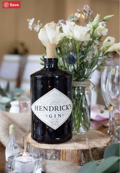 a bottle of hendrick's gin sits on a table with glasses and flowers