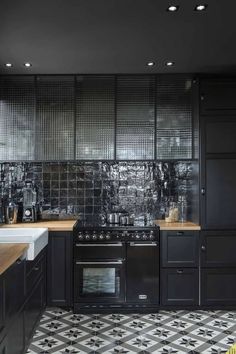 a kitchen with black cabinets and white counter tops, an oven and sink are in the center