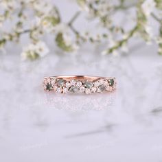 an image of a wedding ring with diamonds on it and some flowers in the background