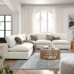 a living room with white couches and rugs on the hardwood floor, windows in the background