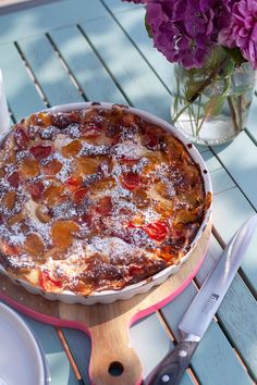 a pie sitting on top of a wooden table next to a vase filled with flowers