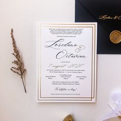 wedding stationery with black envelope and gold foiling on white paper next to other items