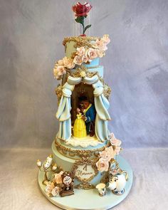 a cake that is decorated with beauty and the beast figurines