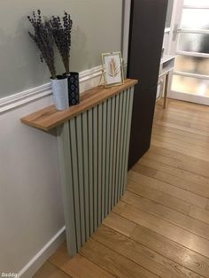 a radiator in the corner of a room next to a vase with flowers