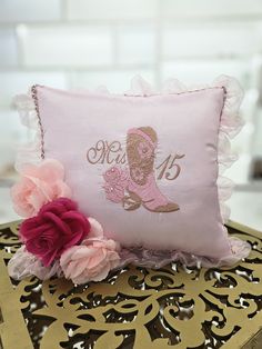 a pink pillow sitting on top of a table next to a flower and a chain