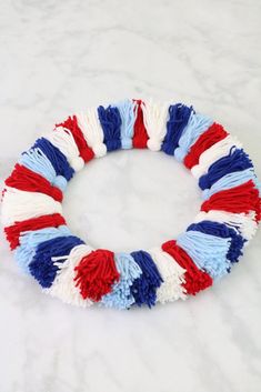 a red, white and blue wreath made out of yarn on a marble countertop