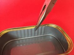 an open tin can with a pair of scissors sticking out of it