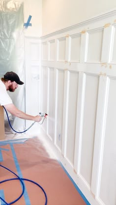 a man with a hose is painting the walls in a room that's being renovated