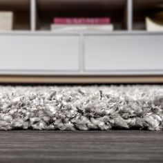 an area rug on the floor in front of a book shelf