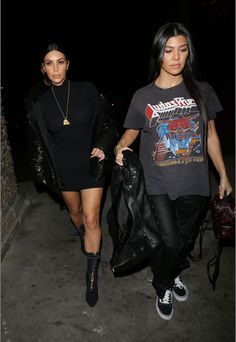 two women walking down the street at night with one carrying a black bag and another wearing a black t - shirt