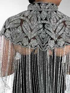 Vega silver beaded cape is a stunning example of intricate craftsmanship and elegant design. The silver beads that adorn the cape are arranged in a dazzling pattern, sparkling in the light and catching the eye of everyone who sees it. The cape also features a pearl beaded pattern that adds an extra level of elegance to the overall look. The beaded embroidery throughout the cape is nothing short of spectacular, with delicate designs and patterns that are exquisitely executed. Features: Open-knit Glamorous Party Shawl, Elegant Sequined Shawl For Festive Occasions, Beaded Shawl For Parties, Elegant Sequin Party Shawl, Elegant Evening Shawl With Sequins, Elegant Embellished Evening Cape, Silver Wedding Shawl, Elegant Silver Shawl For Evening, Luxury Silver Beaded Embellishments