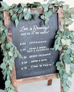 a chalkboard sign with greenery on it that says love is brewing and so is the party