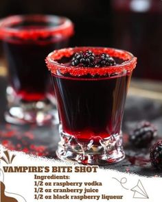 two glasses filled with blackberries on top of a table next to some red liquid