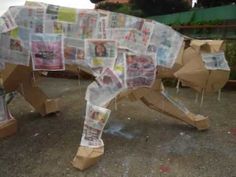 a cow made out of newspaper sitting on the ground