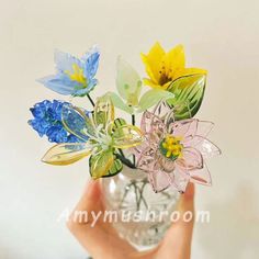 a person holding a glass vase with flowers in it