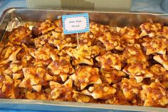 a pan filled with lots of food sitting on top of a blue tablecloth covered table