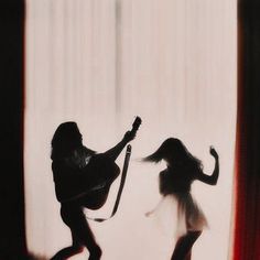 two women are dancing in front of a curtain with their hair blown by the wind