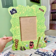 a person holding up a green photo frame with pictures on the front and side of it