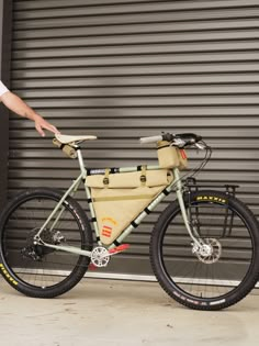 a man standing next to a bike with a bag on the front and back tire