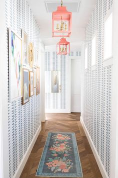 the hallway is decorated in white and pink with pictures on the wall, chandelier hanging from the ceiling