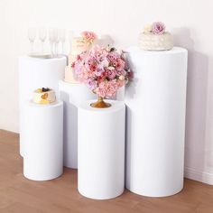 three white vases with flowers and wedding cake on top are sitting next to each other