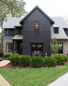 a black house with lots of windows and bushes