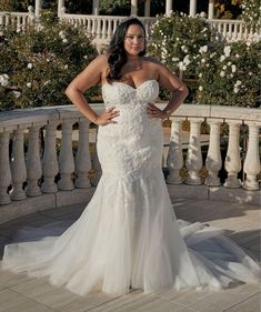 a woman in a wedding dress posing for the camera with her hands on her hips