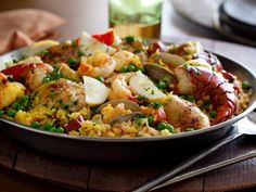 a pan filled with seafood and rice on top of a wooden table