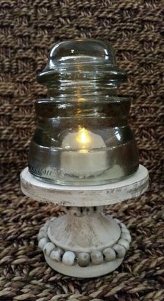 a candle is lit on top of an old fashioned glass jar with pebbles around it